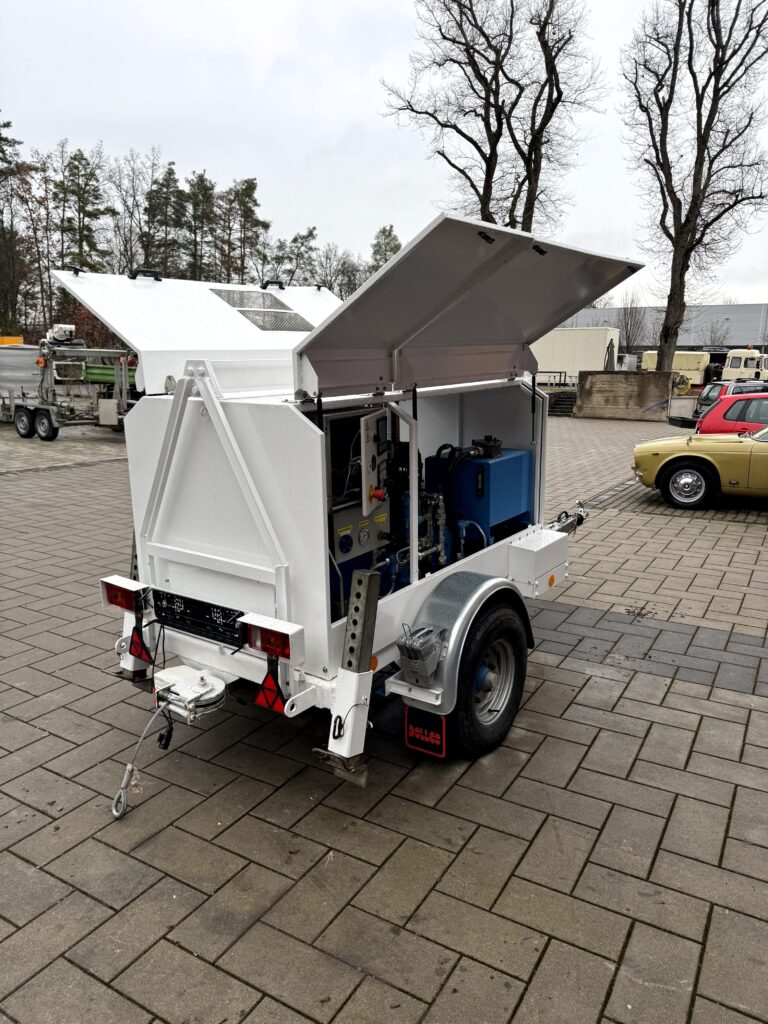 Mobiler Geräte-/Serviceanhänger auf Einachse – weißes, schallgedämmtes Gehäuse mit seitlich und oben geöffneten Klappen, Deichsel und Stützrad; ideal als Generator-, Kompressor- oder Hydraulikaggregat für Baustellen.