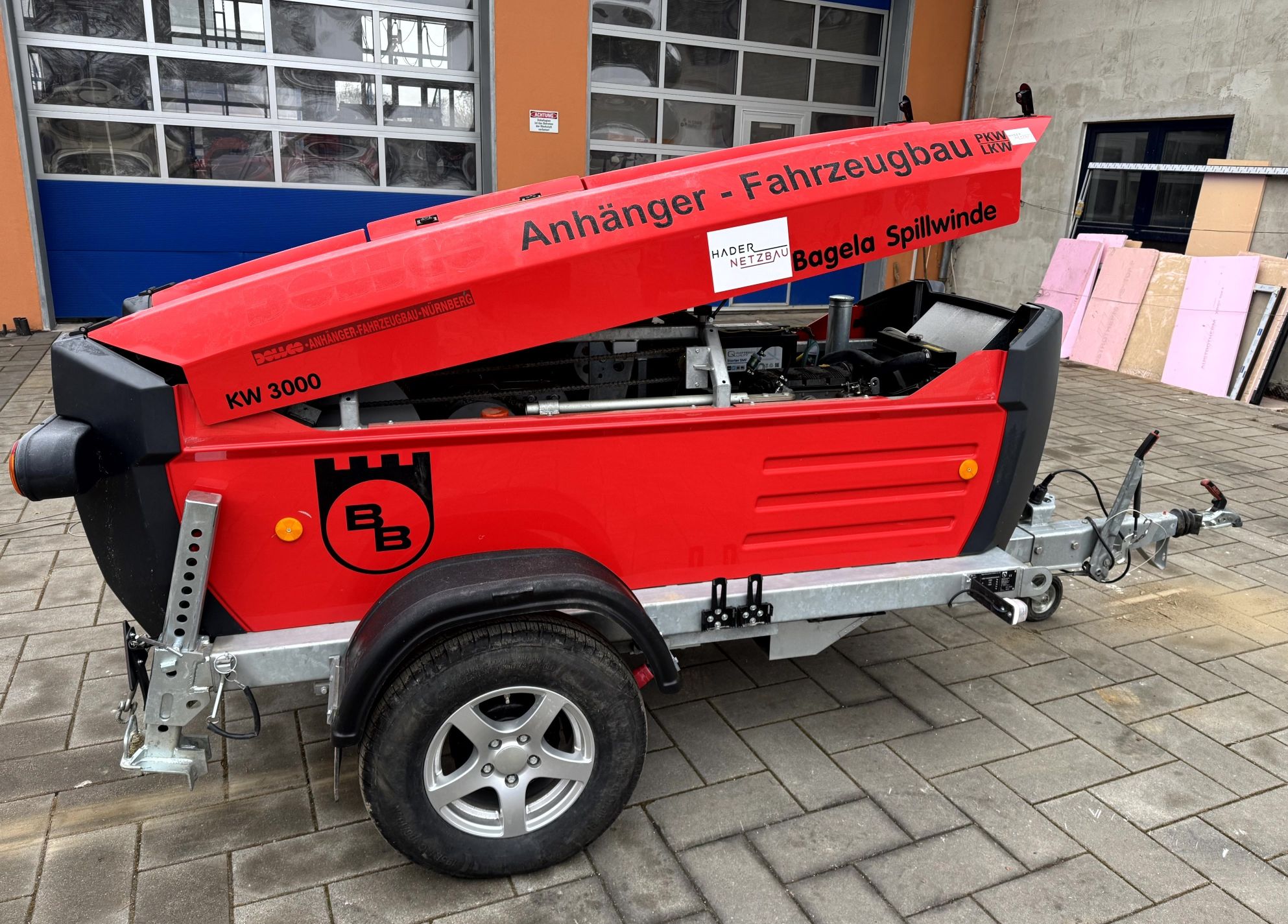 Bagela Spillwinde/Kabelziehwinde auf Trailer – rote, schallgedämmte Haube aufgeklappt, einachsiger Anhänger mit Deichsel und Stützrad; mobile Lösung für Kabelzug im Leitungsbau.