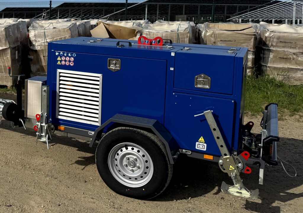 Mobiler Geräteanhänger (Generator/Kompressor) in Blau – schallgedämmte, geschlossene Haube mit Lüftungsgittern, Zugdeichsel, Stützrad und stabilen Abstützungen; robuste Lösung für Baustelle und Dauerbetrieb.