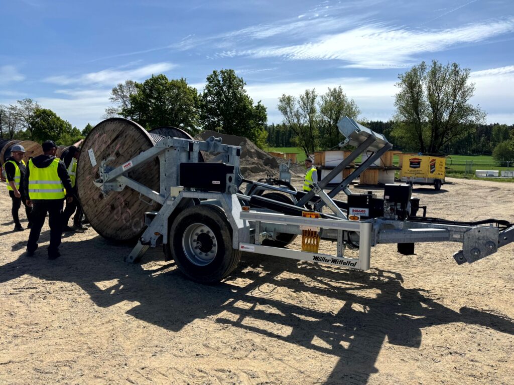 Hydraulisch absenkbarer Kabeltrommelanhänger auf Baustelle – verzinktes Fahrgestell mit Trommelaufnahme und Deichsel, ideal für Kabelverlegung im Leitungsbau/Glasfaser.