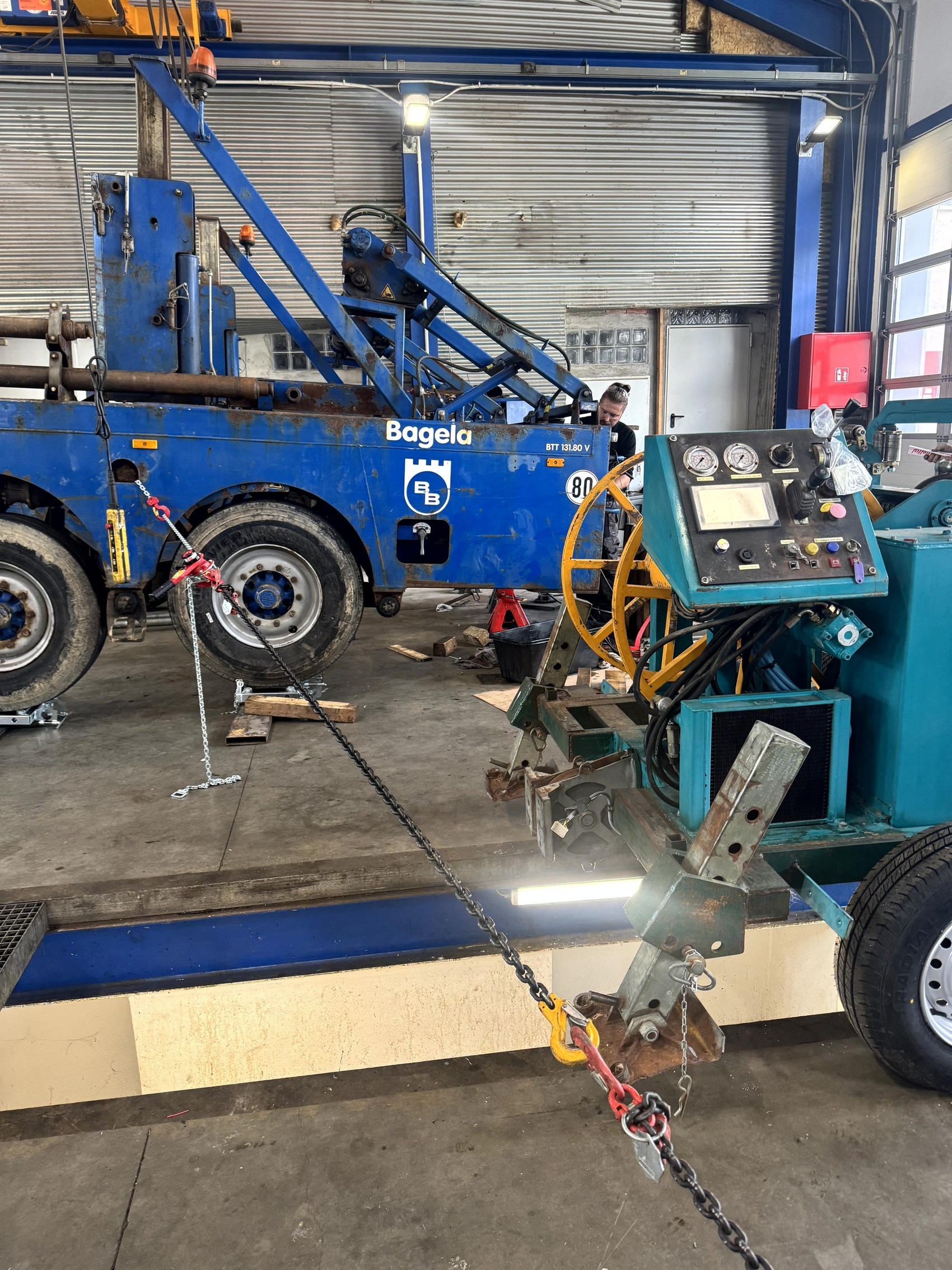 Bagela Kabelziehwinde/Spillwinde in der Werkstatt – mobiles Aggregat mit Bedienpult und Messinstrumenten, über Kette zum Belastungstest am Fahrzeug/Anker befestigt; Service, Prüfung und Instandsetzung für Leitungsbau.